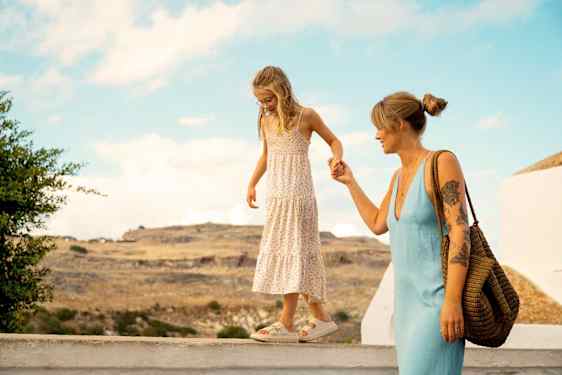 Mor holder datter i hånden, mens hun går på et rækværk