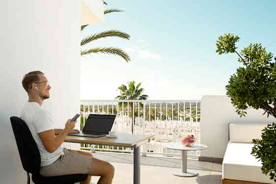 Mand sidder på sin balkon og arbejder