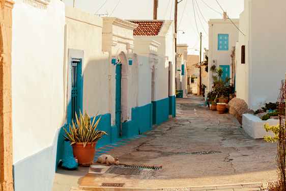En knallert står parkeret i en stræde mellem hvidkalkede huse