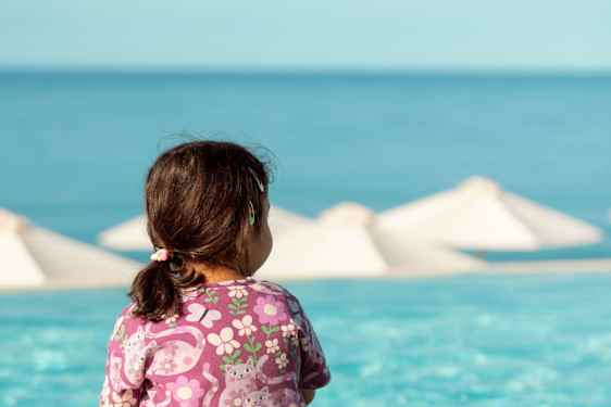 Lille pige sidder ved pool