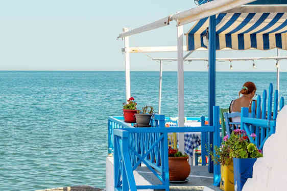 Kvinde sidder på en restaurant ved vandet på Samos