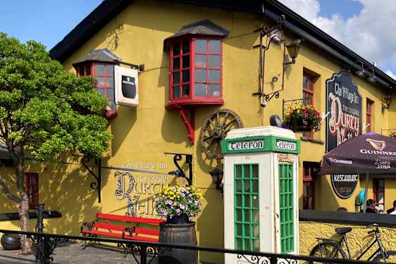 Et gult hus med røde vinduesrammer. Foran huset står en grøn telefonboks.