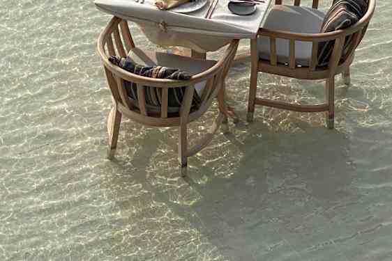 Dækket bord med tilhørerende stole, der står i vandet