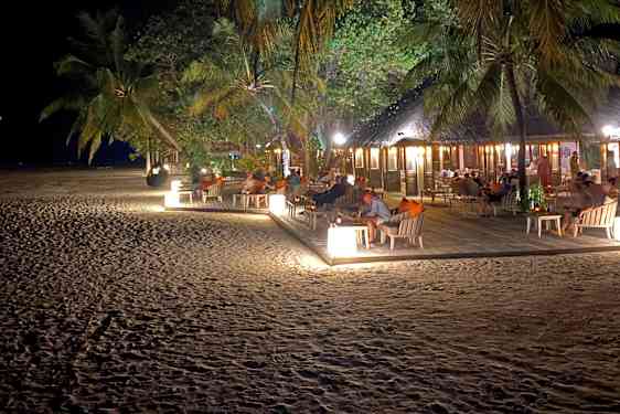 Oplyst strandrestaurant blandt palmer