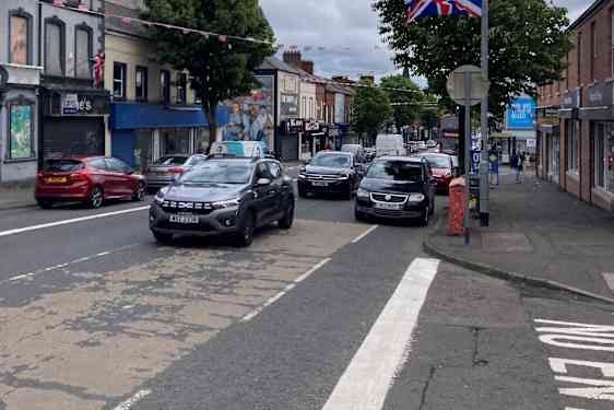 Gade med biler og Storbritanniens flag i lygtepæle