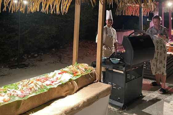 Kok ved grill på stranden om aftenen