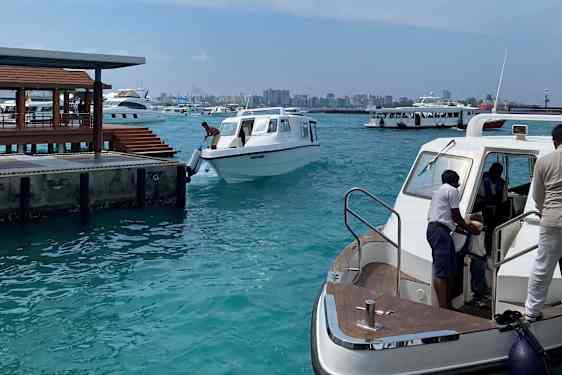 Havn med flere speedbåde. Malés silhuet kan ses i baggrunden