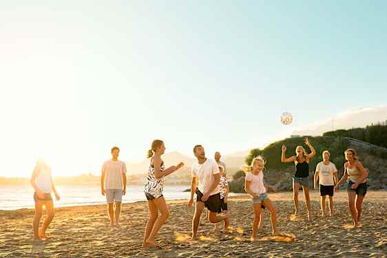 Familie spiller bold på stranden