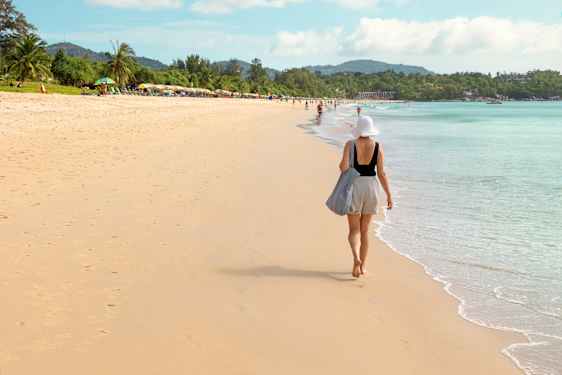 kvinde går på stranden i thailand og nydr solen