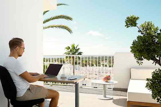 Mand sidder på sin balkon og arbejder