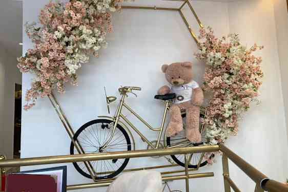 Fin bamse på guldcykel omgivet af blomster