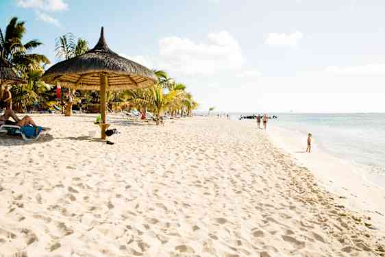 Familie går langs strandkanten