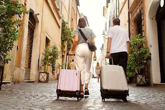 Mand og kvinde går i roms gader med deres kufferter