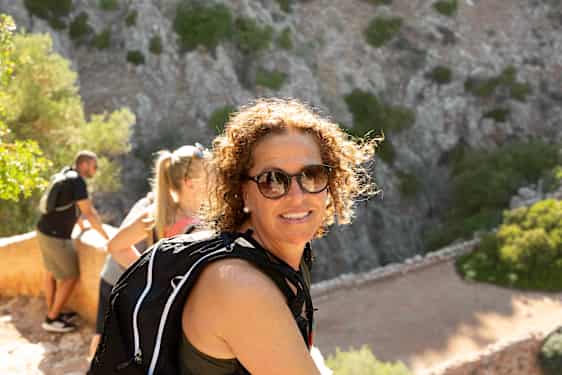 Rejser I flere sammen? Bestil en grupperejse med Spies. På billedet: en kvinde med solbriller griner mod kameraet med venner i baggrunden.