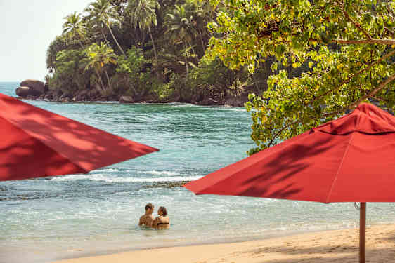 Strand og røde parasoller i Sri Lanka