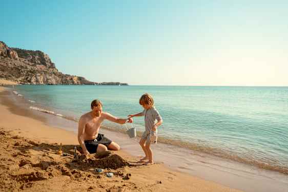 Far og søn leger på stranden