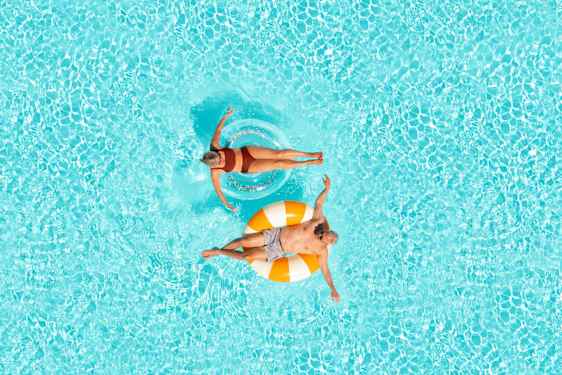 Mand og kvinde ligger i baderinge i pool