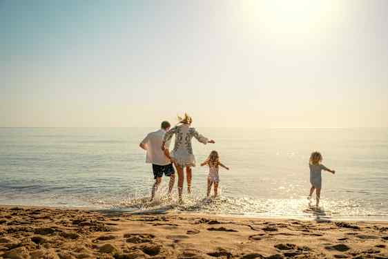 Familie hopper i vandet på stranden