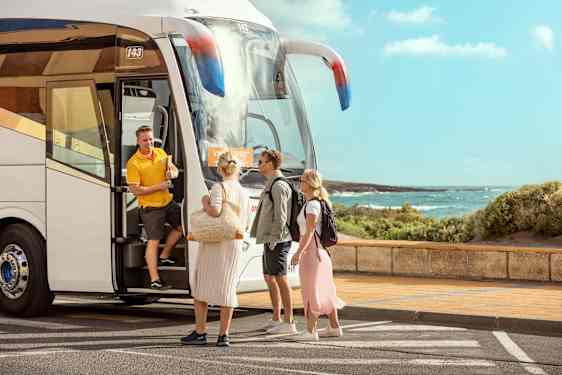 Tre personer møder en guide ved en transferbus