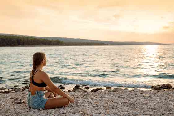Ung kvinde nyder solnedgangen ved stranden i Kroatien