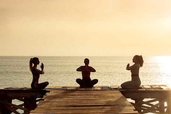 Kvinder dyrker yoga på stranden