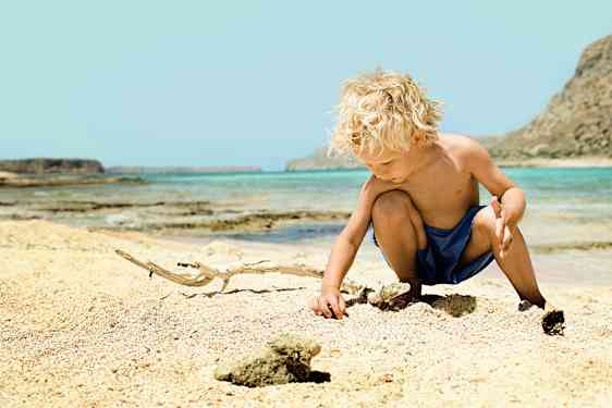 Dreng leger på stranden på Kreta