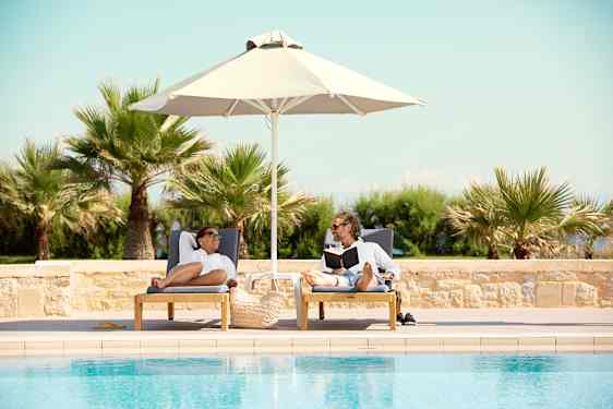 To personer ligger ved pool på en charterrejse med Spies