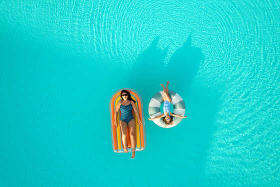 Mor og barn ligger i baderinge i pool