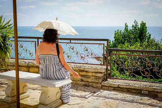 Kvinde under parasol skuer ud over vandet