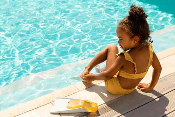 lille pige sidder ved pool