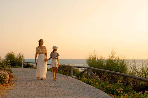 Mor og datter går på strandpromenade