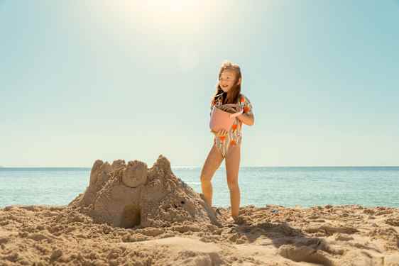 Pige laver sandslot på stranden