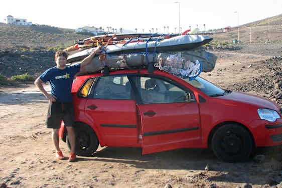 Rød bil med surferudstyr på taget