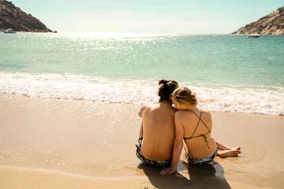 Ett par som sitter på stranden vid vattenbrynet.