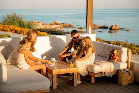 Familie hygger sig på terrasse med kortspil i efterårsferien