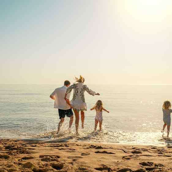 Familie hopper i strandkanten