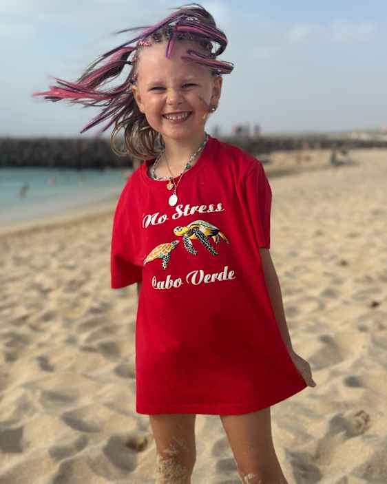 Glad pige iført "no stress" T-shirt på stranden