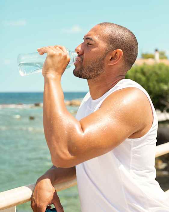 Man drinking water by the ocean