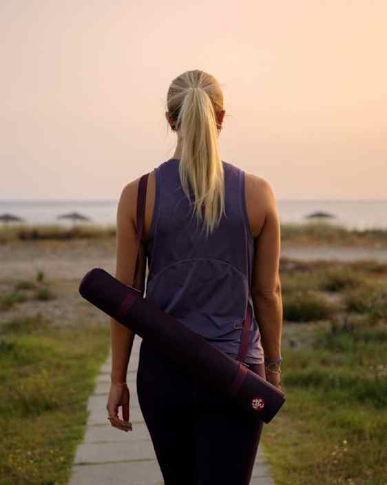 Kvinde på vej til yoga med måtten på ryggen