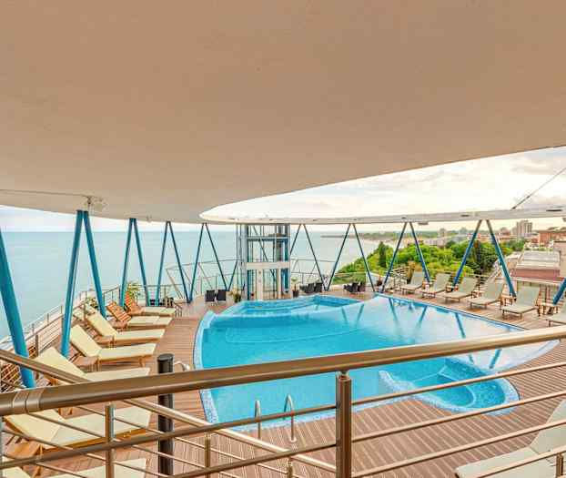 Udendørs pool med boblebad på højt dæk med havudsigt. (AI-genereret tekst)