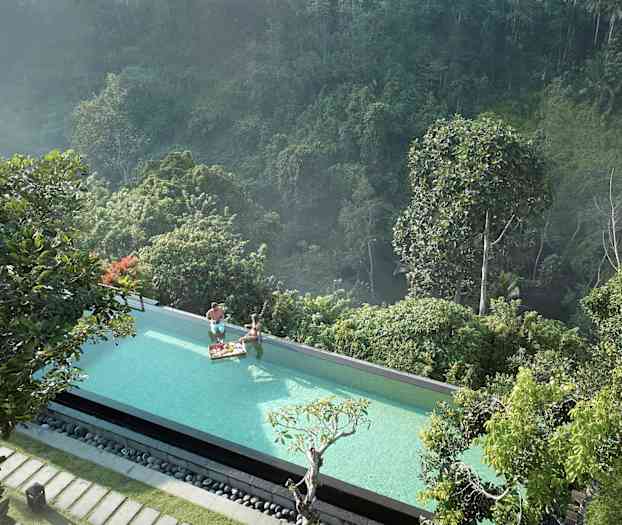 En infinitypool med udsigt over en frodig skov. To personer i poolen med en morgenmadsbakke. (AI-genereret tekst)