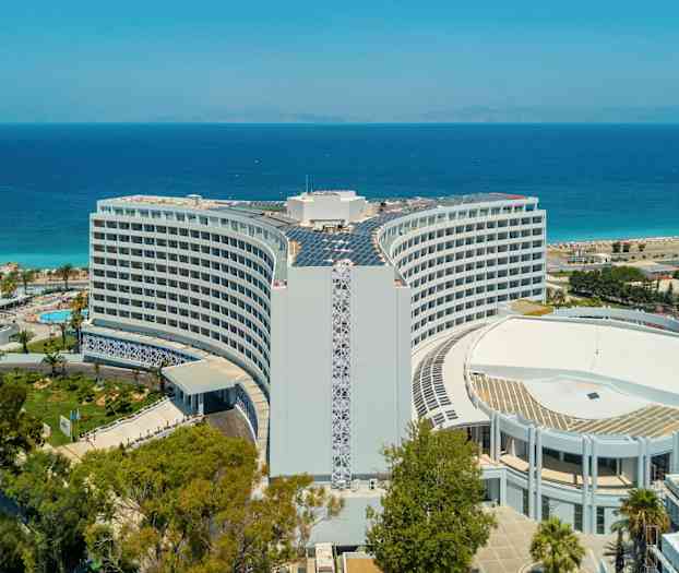 Hotellet med havet og stranden i baggrunden. (AI-genereret tekst)