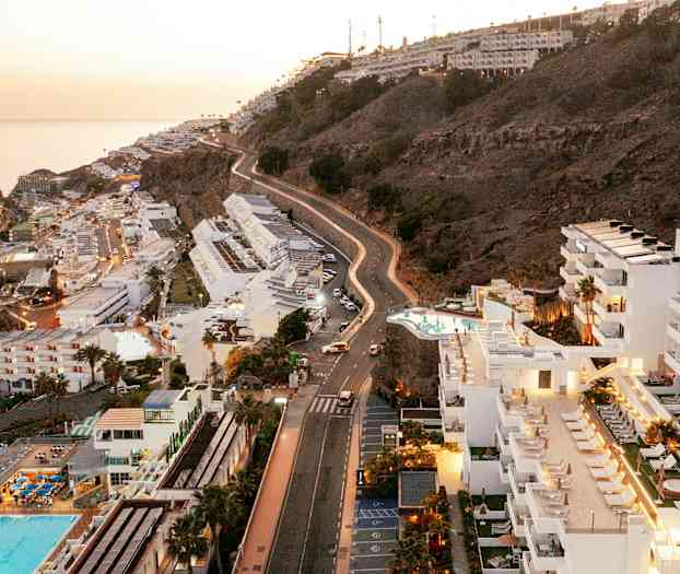 Udsigt over hoteller og skråning ved kysten med havet i baggrunden. (AI-genereret tekst)