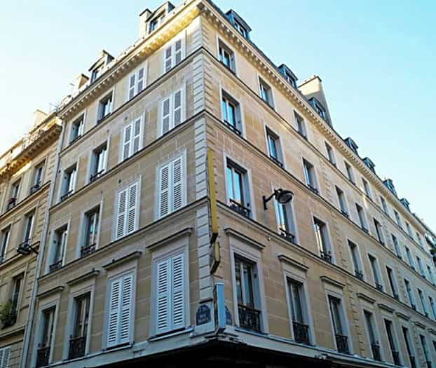 Et hjørnebygning med flere etager og skodder. (AI-genereret tekst)