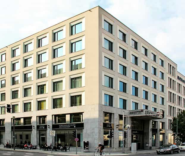 En hjørnebygning med moderne facader og store vinduer, med restaurant og bar i stueetagen. (AI-genereret tekst)