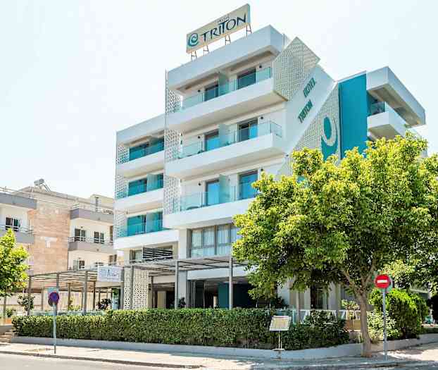 En moderne hotelbygning med fem etager og altaner, omgivet af træer. (AI-genereret tekst)