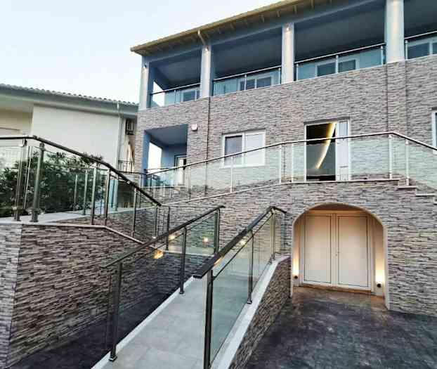 En bygning med sten facade, glasrækværk og en trappe. (AI-genereret tekst)