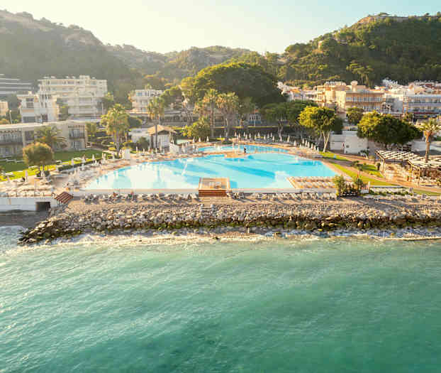 En stor pool ved havet, omgivet af bygninger og grønne områder. (AI-genereret tekst)