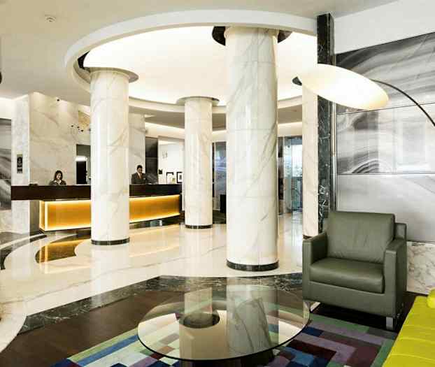 Moderne hotellobby med marmorsøjler, receptionsskranke og siddegruppe. (AI-genereret tekst)