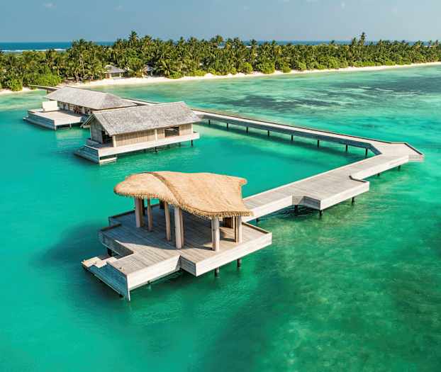 Overvandsbungalower ved en tropisk strand med turkis hav. (AI-genereret tekst)